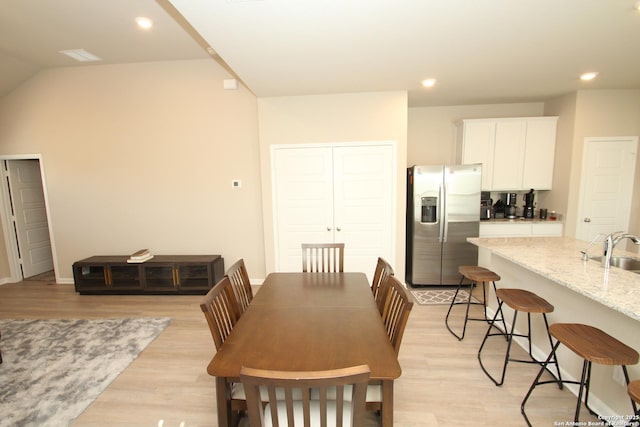 dining room with light wood finished floors, vaulted ceiling, and recessed lighting