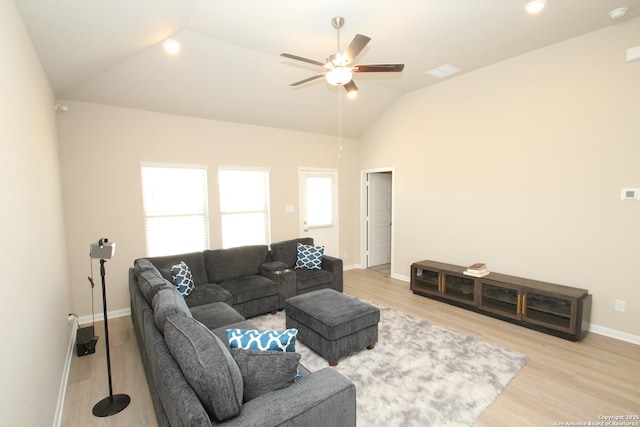 living area with a ceiling fan, vaulted ceiling, light wood-style flooring, and baseboards