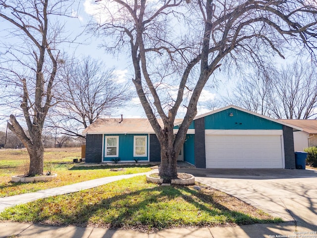 view of front of house with an attached garage, concrete driveway, brick siding, and a front yard