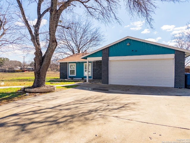 view of front of house featuring a garage, concrete driveway, and brick siding