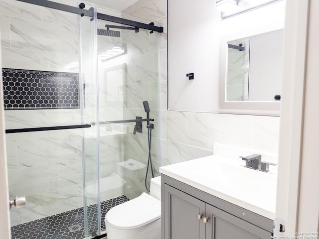 bathroom featuring a textured wall, toilet, vanity, tile walls, and a shower stall