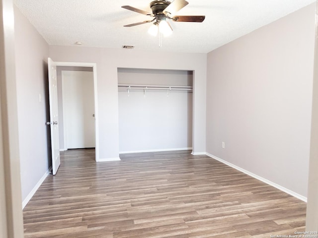 unfurnished bedroom featuring light wood-type flooring, a textured ceiling, visible vents, and a closet