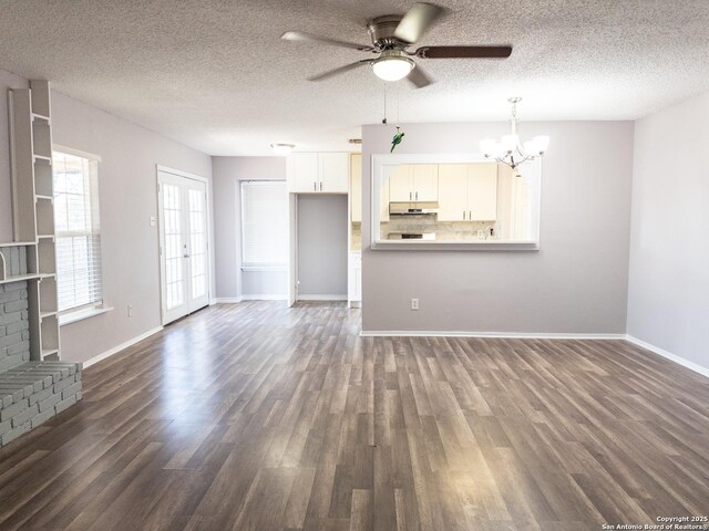 unfurnished living room featuring dark wood-style floors, a fireplace, a textured ceiling, baseboards, and ceiling fan with notable chandelier