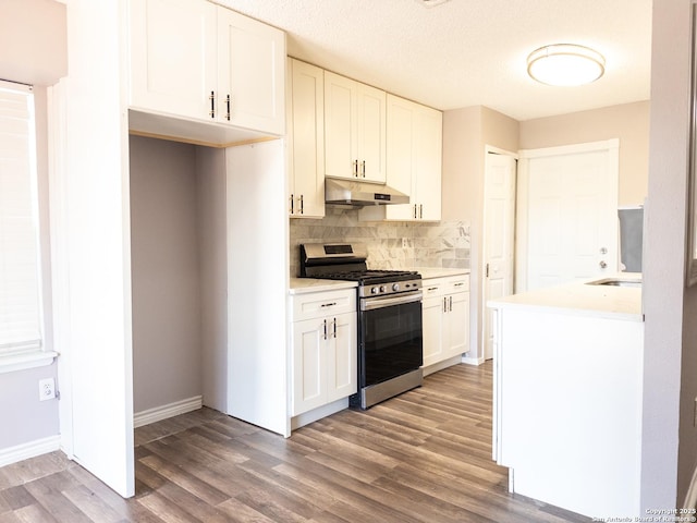 kitchen with under cabinet range hood, white cabinets, light countertops, stainless steel range with gas cooktop, and dark wood-style floors