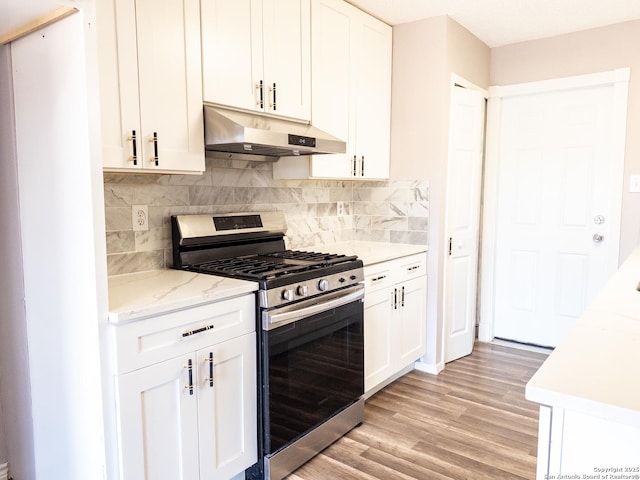 kitchen featuring light stone counters, light wood finished floors, white cabinets, stainless steel gas range, and under cabinet range hood