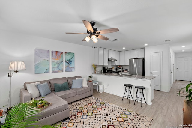 living room with light wood-style flooring, visible vents, ceiling fan, and recessed lighting