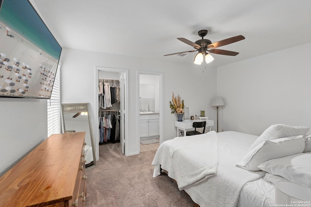 bedroom with connected bathroom, light colored carpet, a ceiling fan, a spacious closet, and a closet