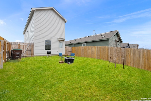 back of house featuring an outdoor fire pit, a lawn, and a fenced backyard