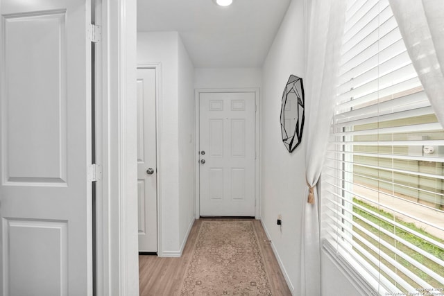 hall featuring light wood-style floors and baseboards