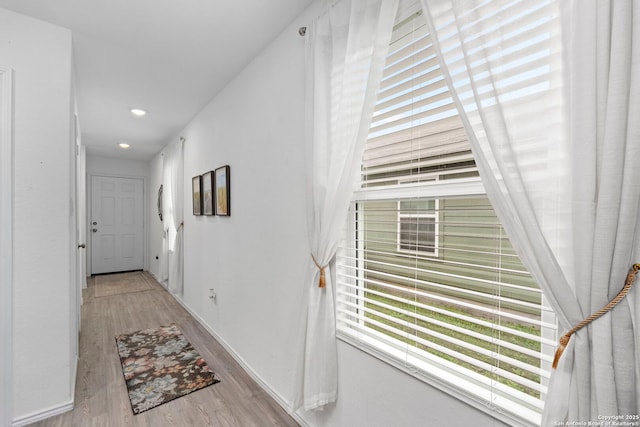 corridor with light wood finished floors, baseboards, and recessed lighting