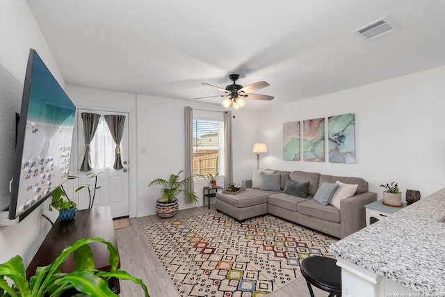 living room with ceiling fan, light wood-style flooring, and visible vents