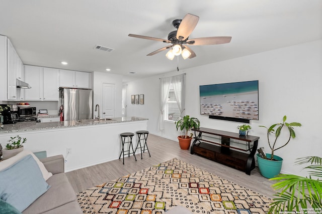 living room featuring light wood finished floors, recessed lighting, visible vents, ceiling fan, and baseboards