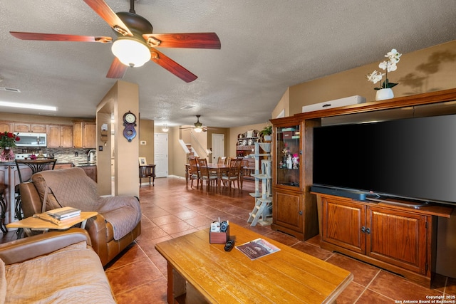 living area featuring tile patterned flooring, a ceiling fan, and a textured ceiling