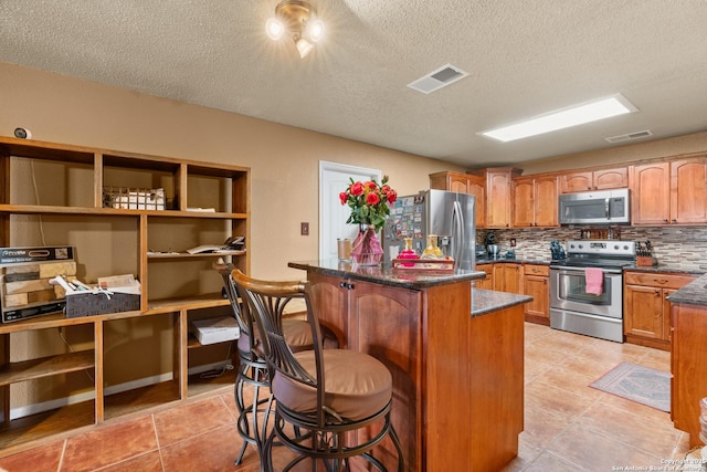 kitchen featuring stainless steel appliances, visible vents, backsplash, a kitchen island, and a kitchen bar