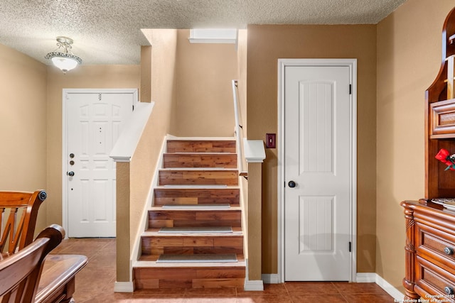 stairs with a textured ceiling, baseboards, and tile patterned floors