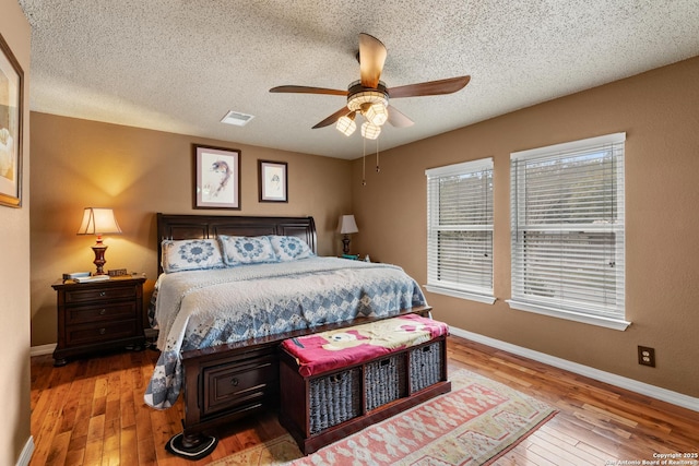 bedroom with baseboards, visible vents, and wood finished floors