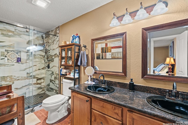 full bath featuring toilet, a shower stall, a textured ceiling, and a sink