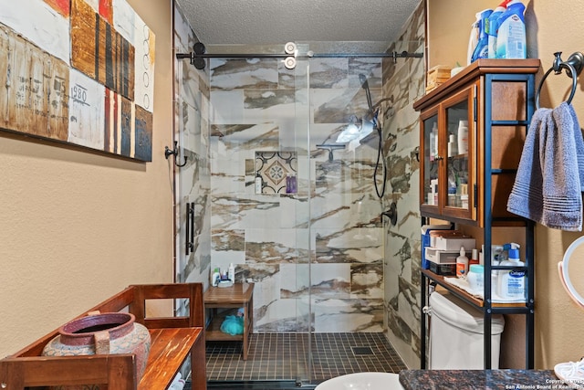 full bathroom with a textured ceiling, a textured wall, a shower stall, and toilet