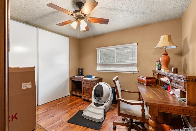 office area featuring light wood-style floors, ceiling fan, and a textured ceiling