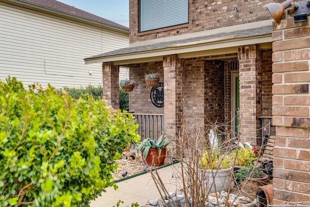 property entrance featuring brick siding and roof with shingles