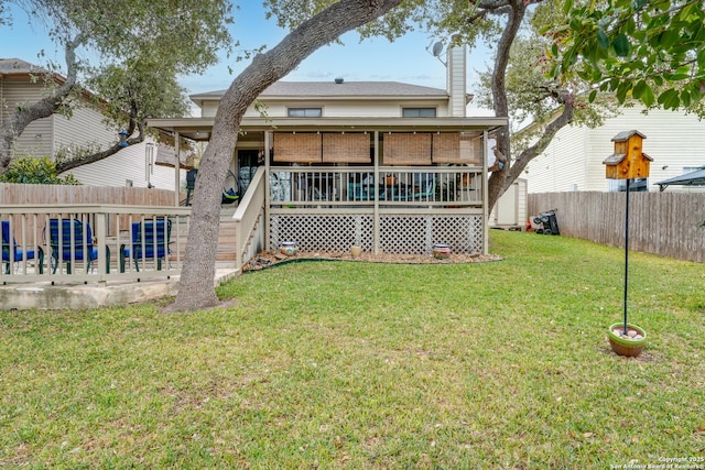 rear view of property featuring a fenced backyard, a chimney, a deck, and a yard