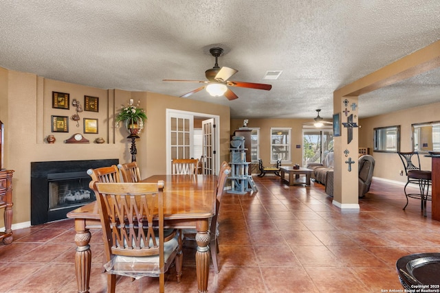 dining space with ceiling fan, a fireplace, visible vents, and tile patterned floors