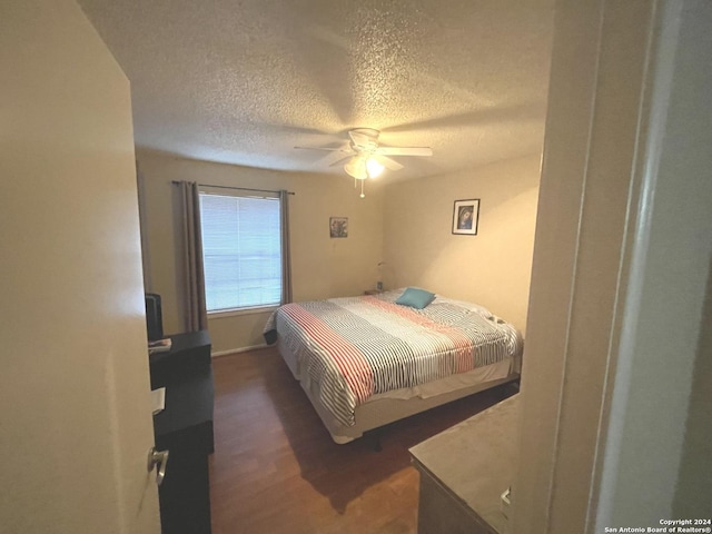 bedroom featuring a textured ceiling, ceiling fan, and dark wood-type flooring