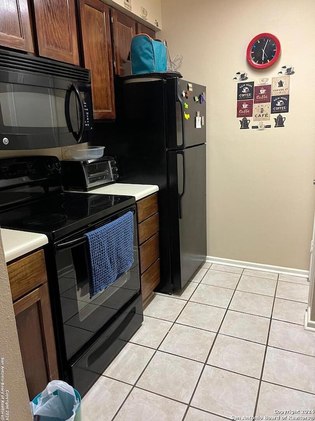 kitchen featuring light tile patterned floors, a toaster, baseboards, light countertops, and black appliances