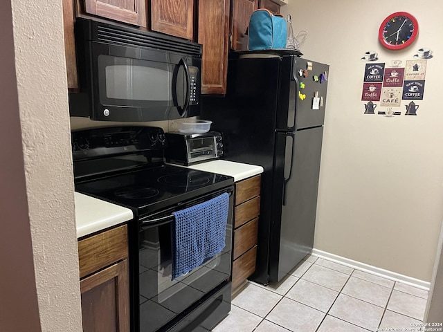 kitchen with a toaster, light countertops, black appliances, and light tile patterned floors