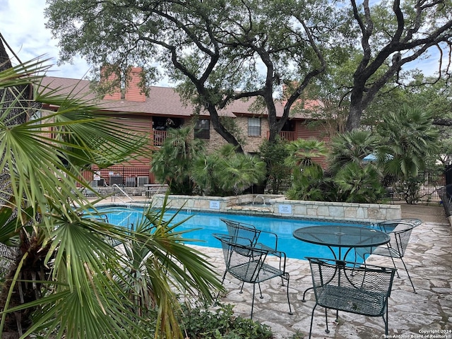 outdoor pool featuring fence and a patio