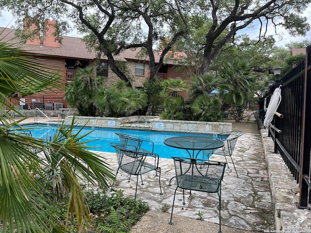 pool with a patio area and fence