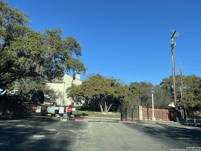 view of street featuring curbs, a gated entry, traffic signs, and a gate