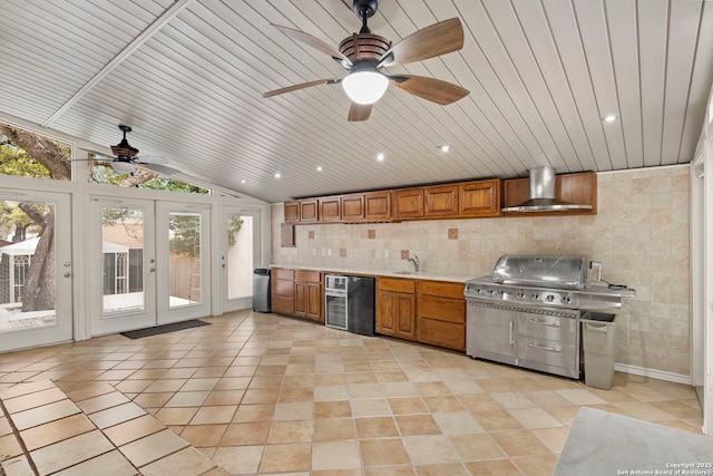 kitchen featuring lofted ceiling, wall chimney exhaust hood, brown cabinetry, and light countertops