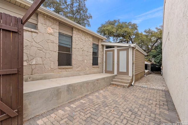 view of exterior entry with stone siding and a patio area