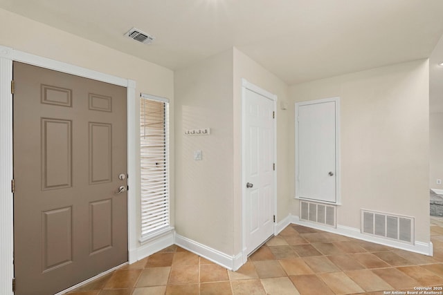 foyer entrance featuring light tile patterned floors, baseboards, and visible vents