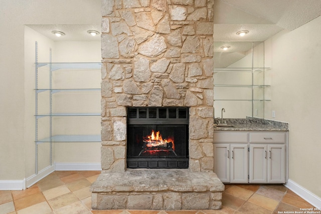 interior details with baseboards, a fireplace, a textured ceiling, and a sink