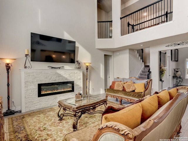 living room with baseboards, a fireplace, stairway, and a towering ceiling