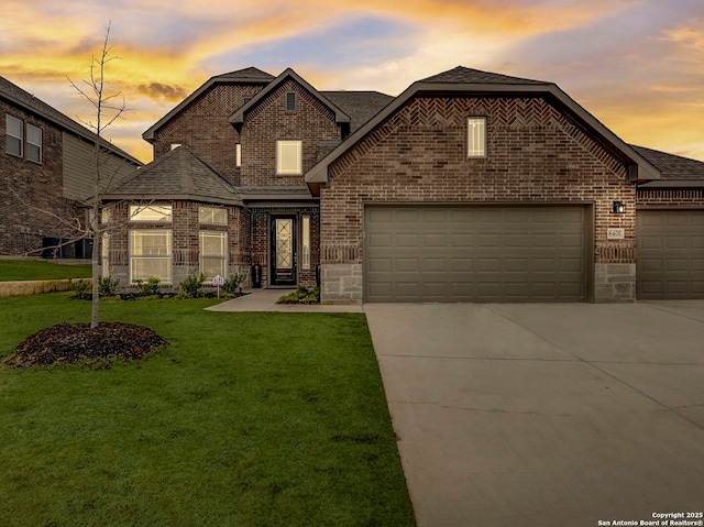 french country style house featuring a garage, concrete driveway, brick siding, and a lawn