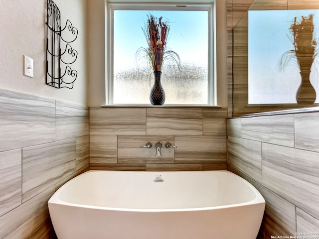 full bathroom with a freestanding tub and tile walls