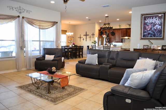 living room with light tile patterned floors, recessed lighting, ceiling fan with notable chandelier, visible vents, and baseboards