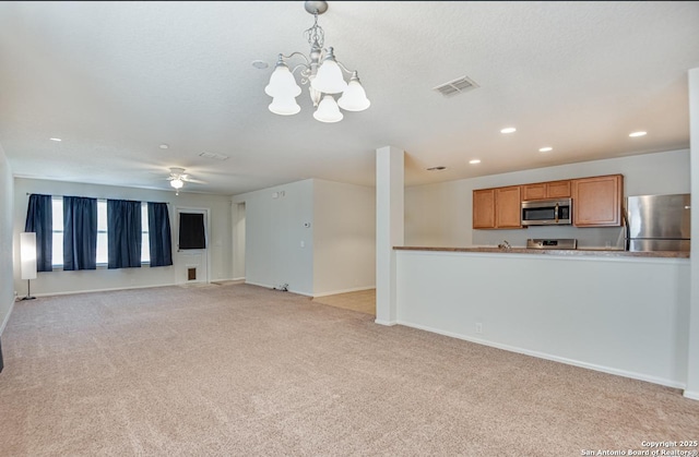 unfurnished living room featuring recessed lighting, ceiling fan with notable chandelier, light colored carpet, visible vents, and baseboards