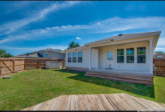 rear view of house featuring a fenced backyard, a lawn, a wooden deck, and ceiling fan