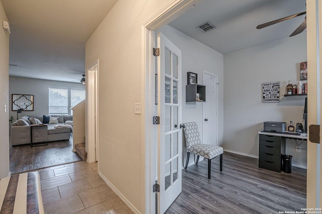 hall with visible vents, baseboards, and wood finished floors