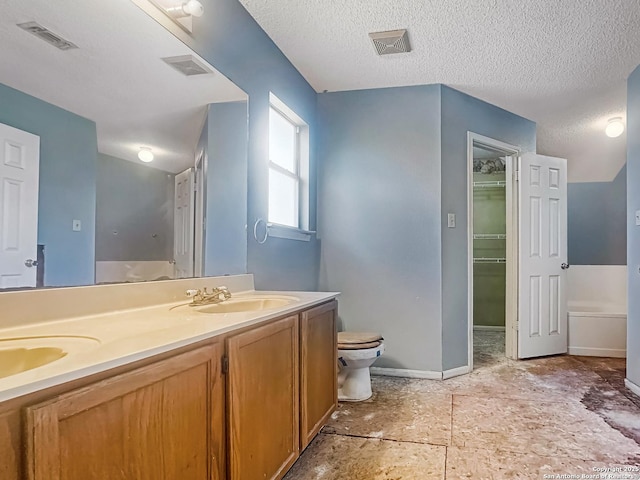 bathroom with double vanity, visible vents, a walk in closet, and a sink