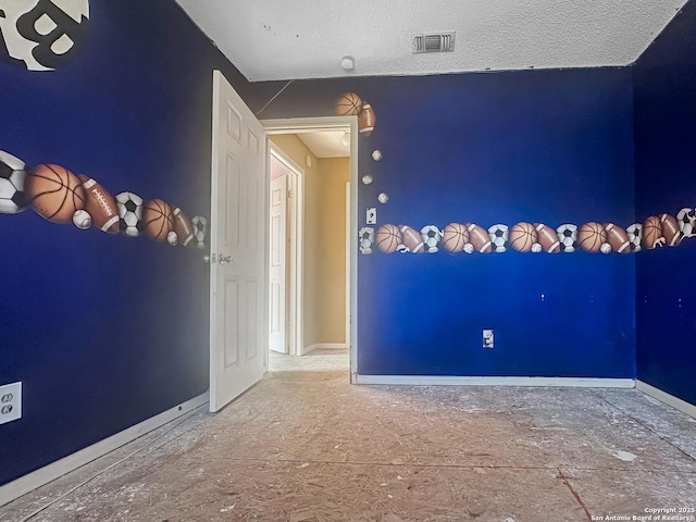 spare room featuring visible vents, a textured ceiling, and baseboards