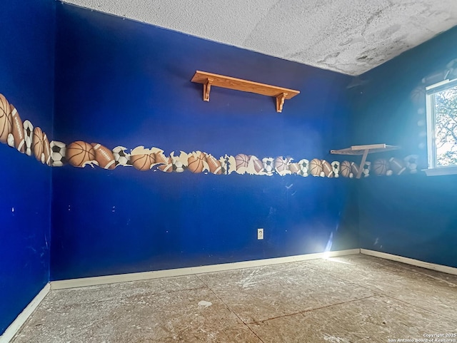 empty room featuring a textured ceiling and baseboards