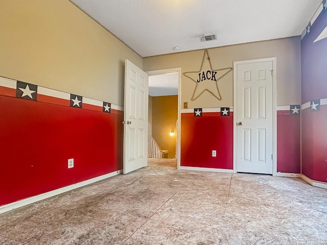 unfurnished room featuring visible vents, a textured ceiling, and baseboards