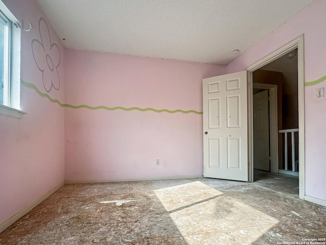 spare room with plenty of natural light, a textured ceiling, and baseboards