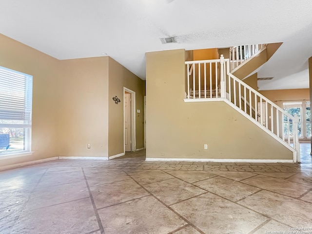 unfurnished room featuring stairway, visible vents, and baseboards