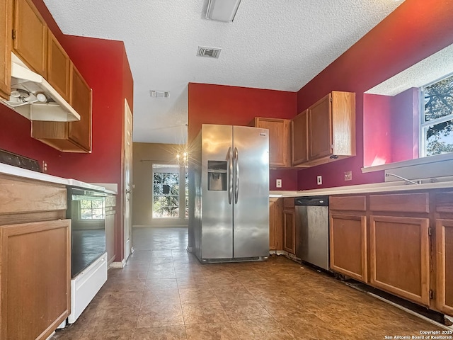 kitchen with light countertops, appliances with stainless steel finishes, brown cabinetry, and visible vents